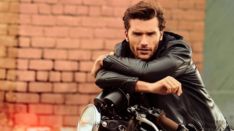 Posing on a motorcycle, Aurelien Muller sports a leather jacket and jeans from IKKS.