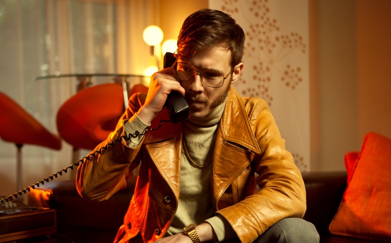 Man 70s Style Glasses Tan Brown Leather Jacket Turtleneck Gold Jewelry The leather jacket is one of the quintessential men's styles of the '70s.