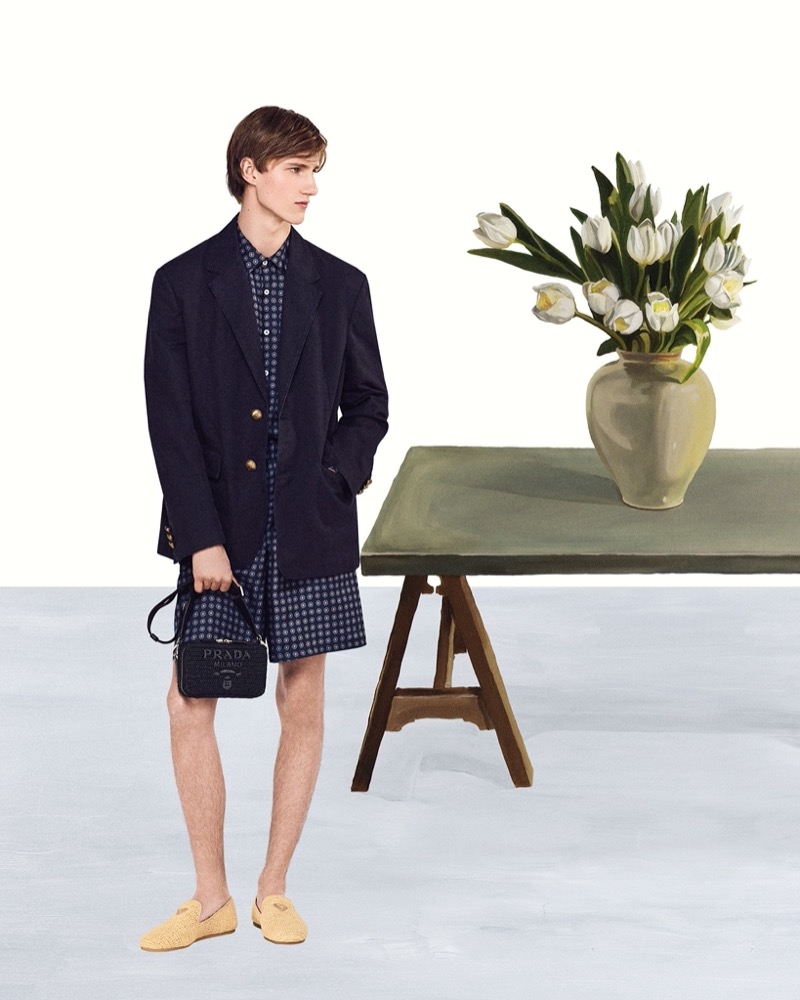 Prada Summer 2024 Campaign 003 Finlay Robinson sports a printed short set with a blazer and Prada's crochet Brique bag for the brand's summer 2024 campaign.